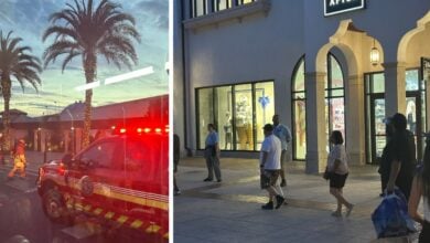 Guests gather outside Disney Springs shops at dusk as a firetruck with flashing lights responds near palm trees, adding excitement.
