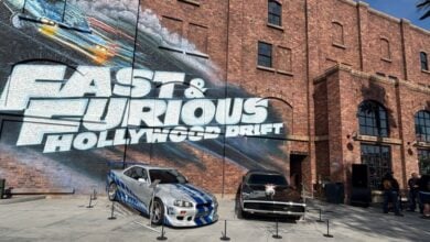 Fast & Furious movie cars on display beneath the iconic "Fast & Furious Hollywood Drift" mural at Universal Studios.
