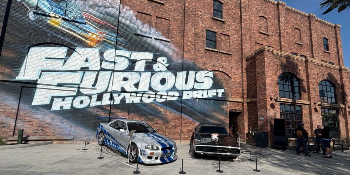 Fast & Furious movie cars on display beneath the iconic "Fast & Furious Hollywood Drift" mural at Universal Studios.