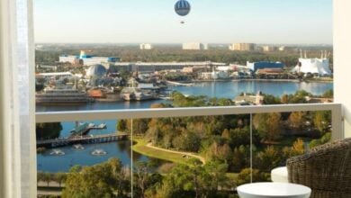 Balcony view at Disney Springs hotel, overlooking lake, lush landscape, iconic attractions, and Aerophile balloon in the sky.
