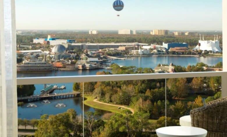 Balcony view at Disney Springs hotel, overlooking lake, lush landscape, iconic attractions, and Aerophile balloon in the sky.