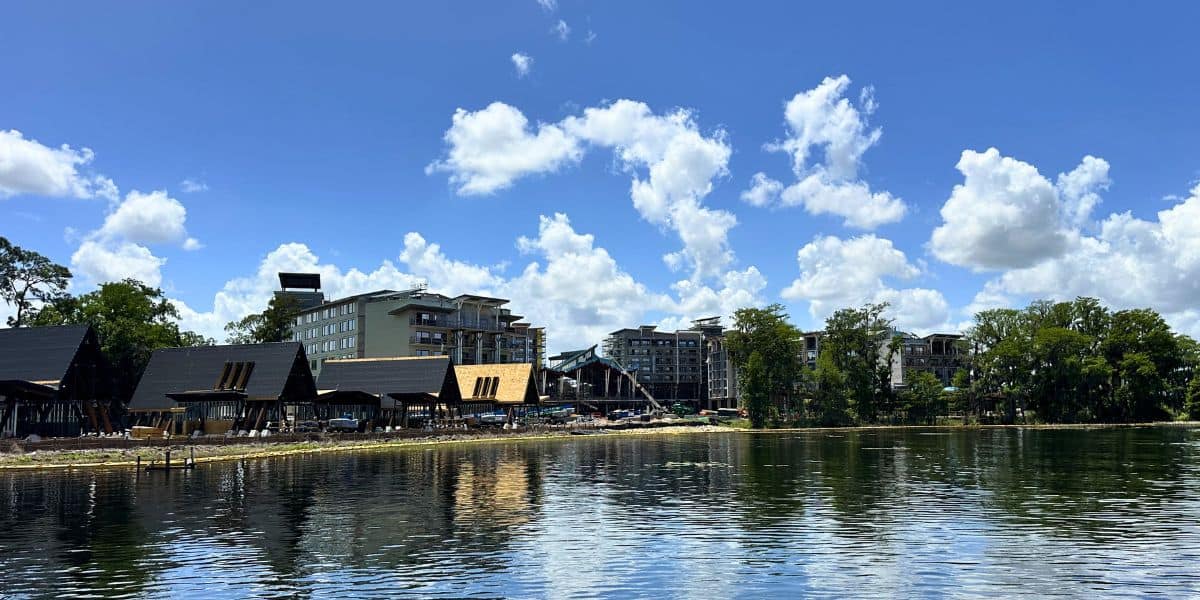 Lakeside modern and wooden buildings evoke Disney Orlando Resort, hinting at exciting new theme park-inspired developments.