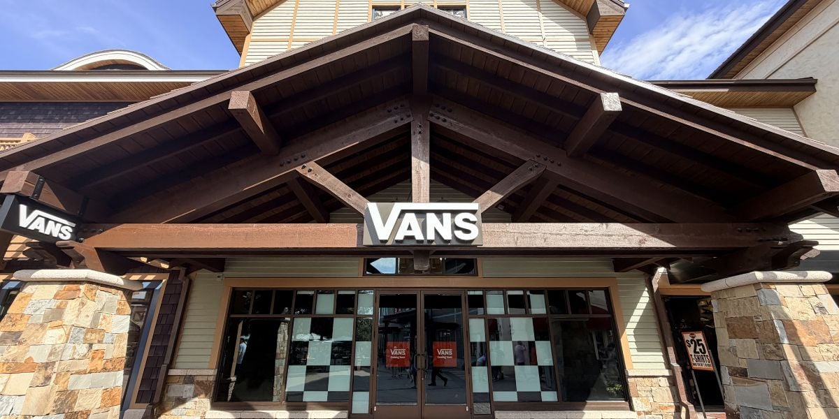 Themed Vans store facade with rustic wooden beams and stone columns, inviting guests on a sunny day at the park.