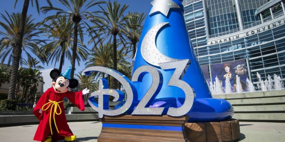 Mickey Mouse, dressed as the Sorcerer’s Apprentice, greets excited Disney fans beside a giant blue D23 sign at the entrance to the convention center, setting the stage for an unforgettable D23 Experience.