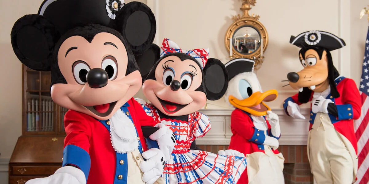 Mickey, Minnie, Donald, and Goofy don colonial outfits in a US flag-adorned room, radiating Disney’s post-fireworks patriotism.