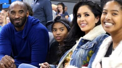 Vanessa Bryant and three companions share a joyful moment courtside at a basketball game, smiling for the camera in a scene filled with the emotional spirit of Disney’s moving Kobe Tribute event.