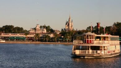 A ferryboat glides across the Seven seas Lagoon in front of the Magic Kingdom
