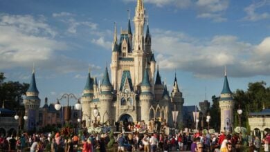 Guests fill Main Street, U.S.A., gathering in front of Cinderella Castle at Magic Kingdom on a bright, sunny day.