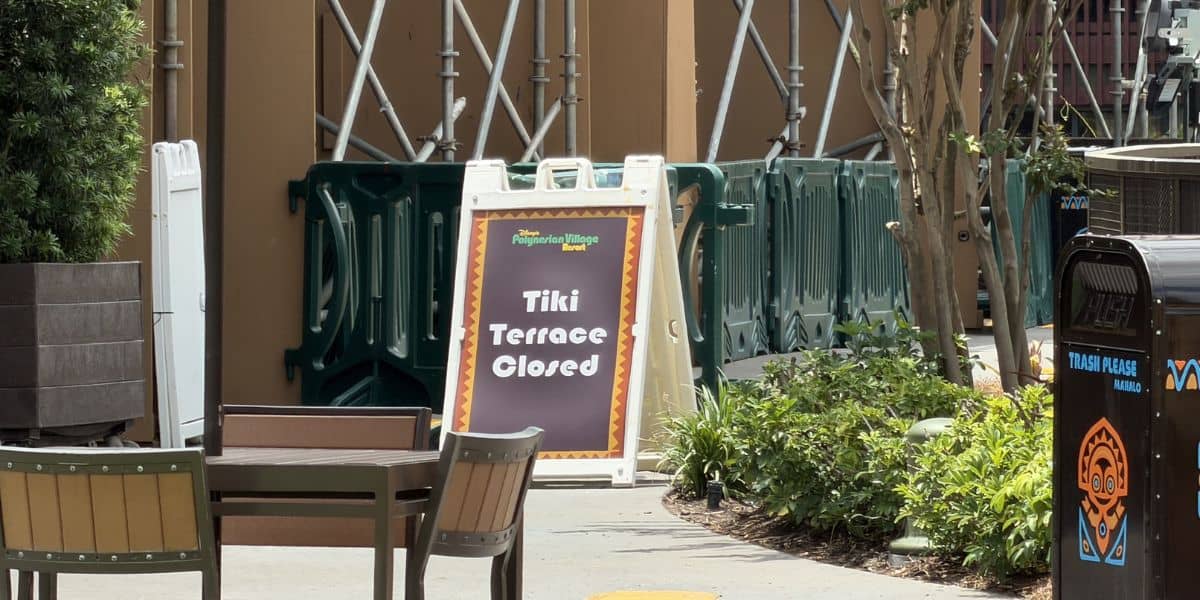 A "Tiki Terrace Closed" sign is displayed by construction barriers at the Polynesian Village Resort, with empty patio tables and chairs in the outdoor seating area.
