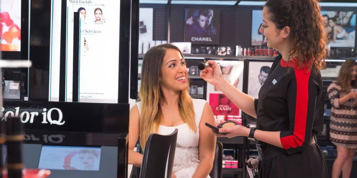 A makeup artist enhances a guest’s look at a lively Pop-Up cosmetics store inside Disney Springs, where beauty experiences add to the magic of your visit.