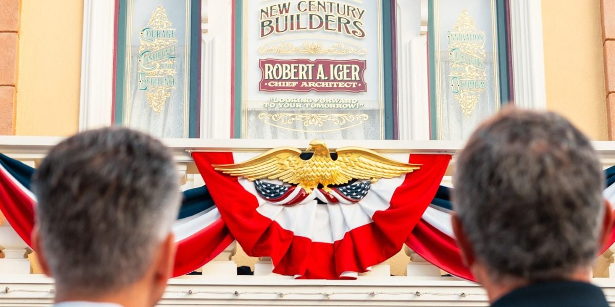 Guests admire a building sign honoring Robert A. Iger, set above a patriotic eagle and festive bunting, capturing the spirit of Disney’s legacy and leadership.