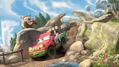 Vibrant cartoon cars zoom along an adventurous dirt racecourse at a family amusement park, kicking up mud as excited riders cheer and scenic rock formations add to the thrilling attraction.