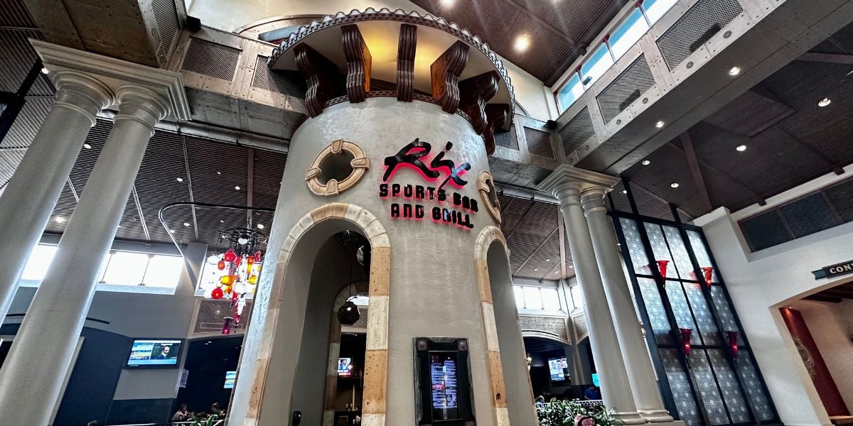 The iconic round Rix Sports Bar and Grill structure welcomes Disney World guests inside a vibrant, contemporary dining space, inviting fans to relax, watch the game, and savor great food in an energetic resort atmosphere.