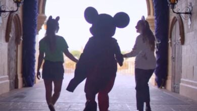 Disney World guests walk with Mickey Mouse in Magic Kingdom