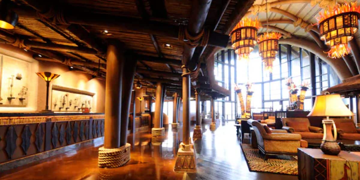 Inviting hotel lobby at a Disney World Deluxe Resort, featuring striking wooden beams, expansive windows, tribal-inspired decor, and plush seating areas—creating an immersive setting where guests can relax in signature Disney comfort before diving into the magic of the parks in October 2026.