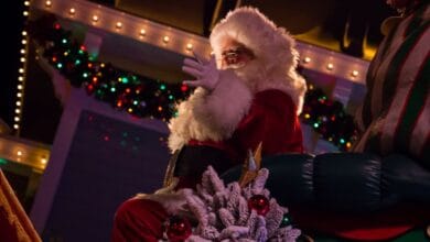 Santa Claus waving from a parade at Disneyland Park.