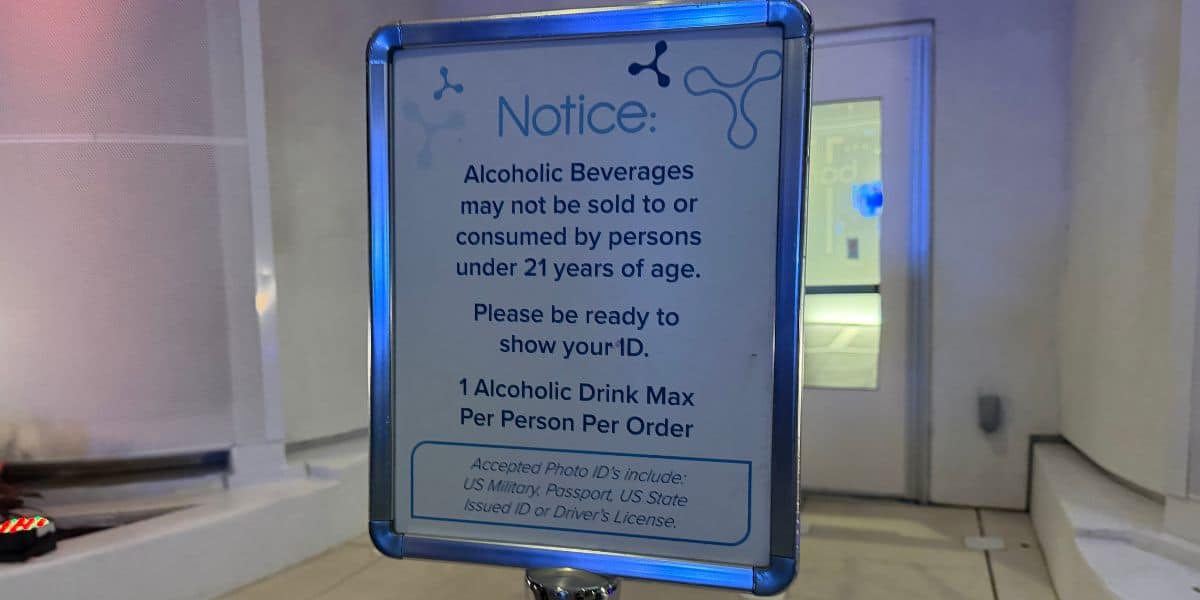 Sign at the theme park stating guests must be 21 or older to purchase alcohol, limited to one drink per person with valid ID required; approved forms of identification detailed below.