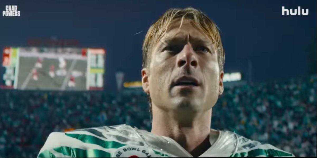 Chad Powers, suited up in his football uniform, gazes upward beneath the dazzling stadium lights, with the energetic crowd and scoreboard behind him capturing all the excitement and showtime spirit of game day.