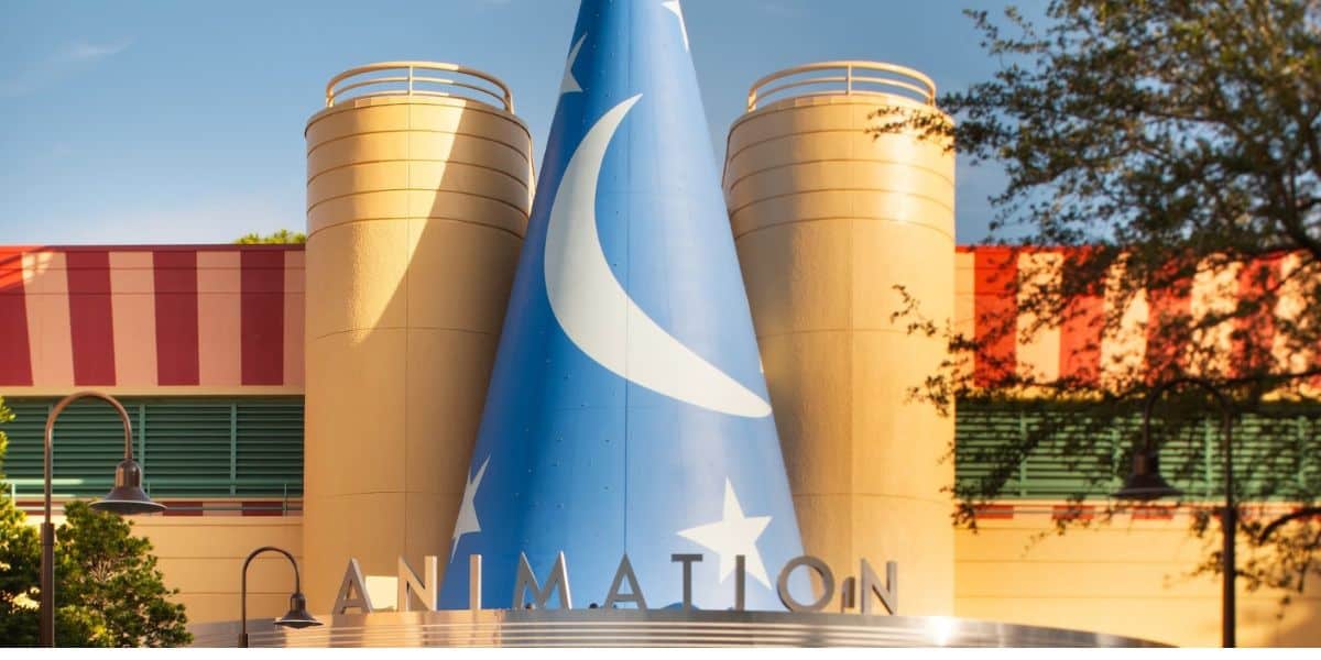 The iconic Sorcerer Hat from Disney’s Hollywood Studios, decorated with moons and stars, stands proudly in front of the animation building on a bright, clear day.