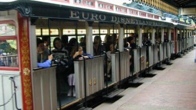 The Euro Disneyland Railroad train waits at the station platform as excited guests sit aboard, ready to embark on a scenic journey around Disneyland Paris.