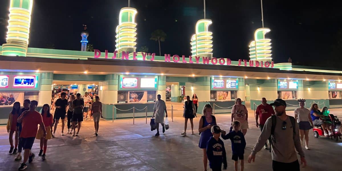 Guests stroll beneath the vibrant neon lights at the entrance to Disney’s Hollywood Studios
