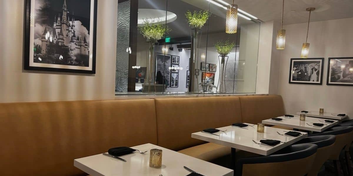 Step into Steakhouse 71 at Disney’s Contemporary Resort, where sleek tan booths, crisp white tables, and black napkins set a modern vibe under classic black-and-white Disney photos on the walls—a must-try dining spot for theme park fans, with reservations highly recommended.
