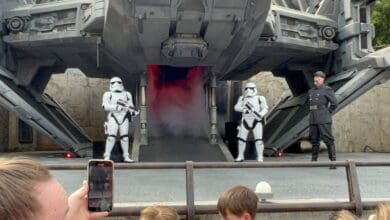 Two Stormtroopers and an Imperial officer standing before a First Order transport ship at Star Wars: Galaxy’s Edge in Disney’s Hollywood Studios.