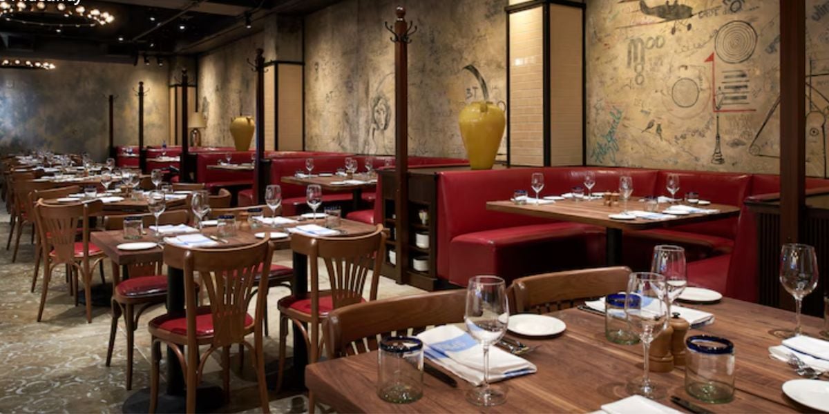 Dining tables and red booths in a festive holiday-themed pop-up restaurant with mural-covered walls.
