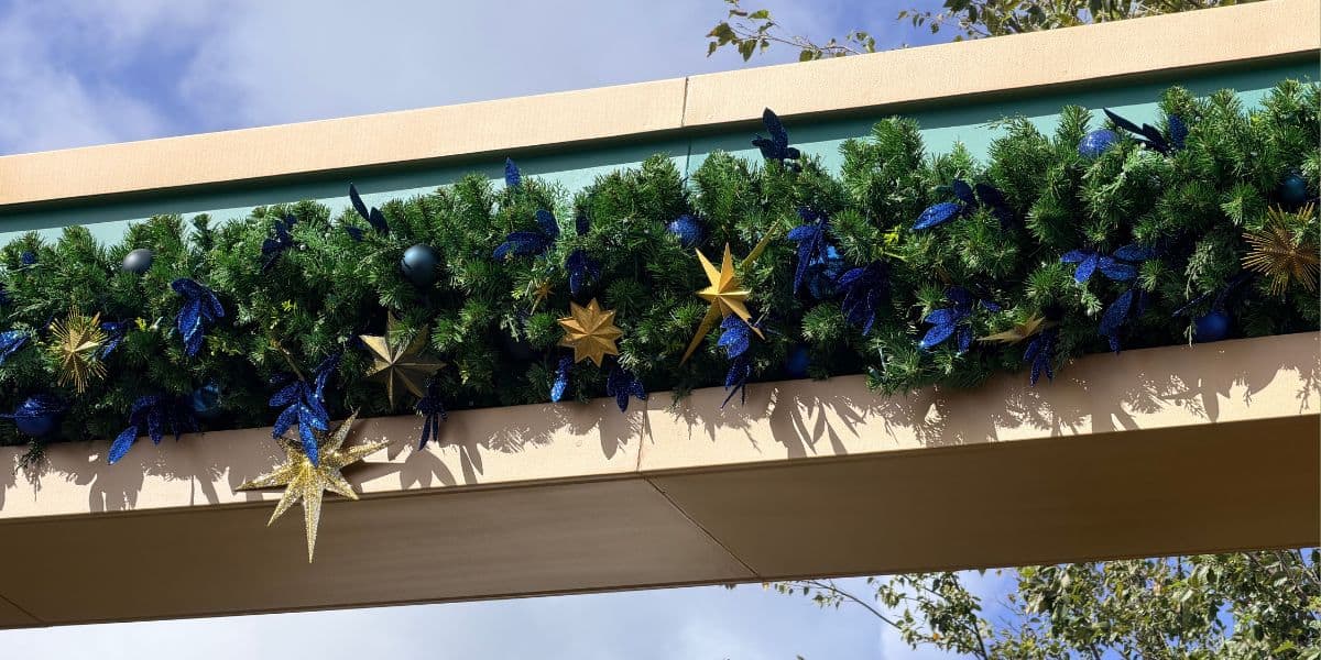 Holiday garland with blue ornaments and gold stars at the Epic Universe entrance.