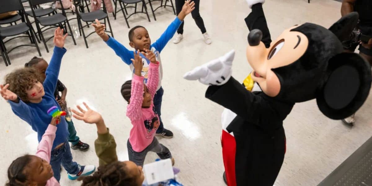Mickey Mouse greets a group of children.