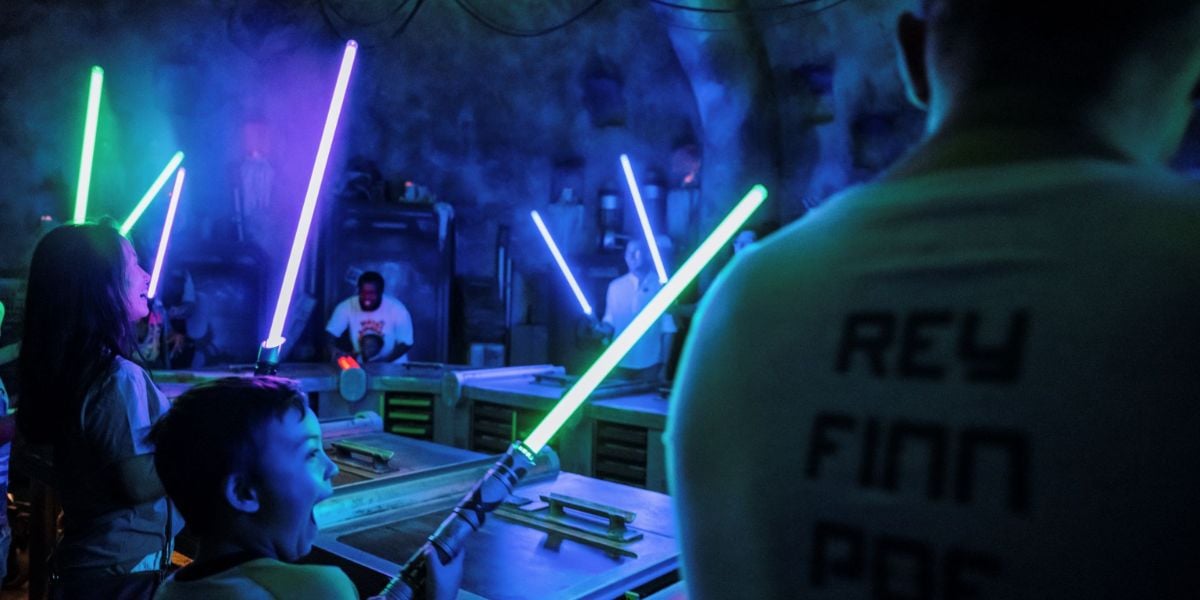 Guests ignite lightsabers during a building experience at Savi’s Workshop in Star Wars: Galaxy’s Edge
