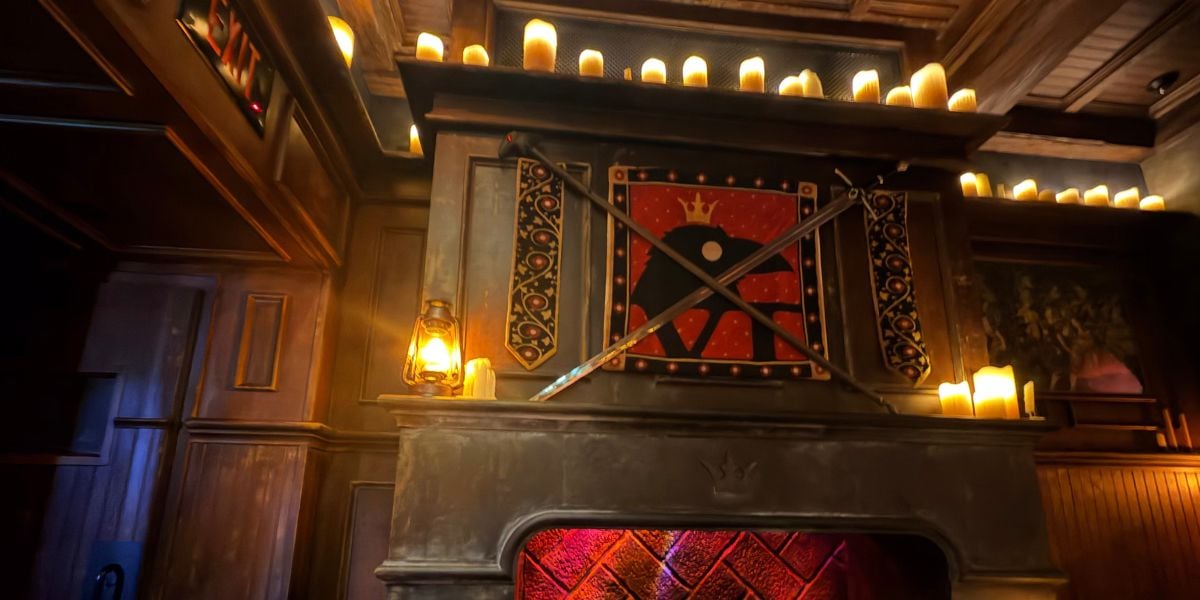 Fireplace with a raven crest and crossed swords in the West Wing at Be Our Guest Restaurant.