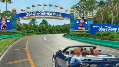 a blue car full of disney fans drives toward walt disney world entrance